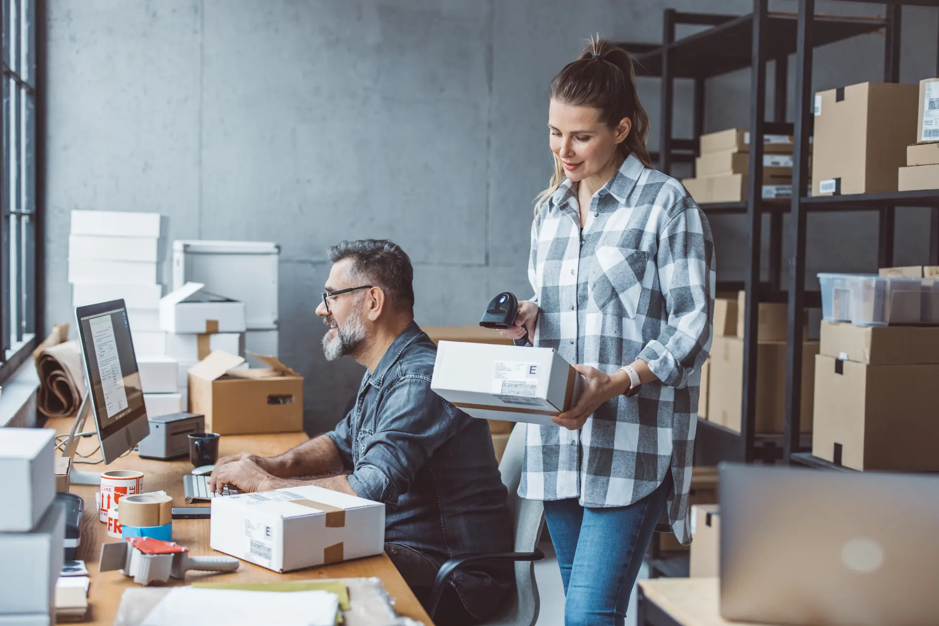 Two colleagues at their workstation preparing and scanning a parcel before it ships.